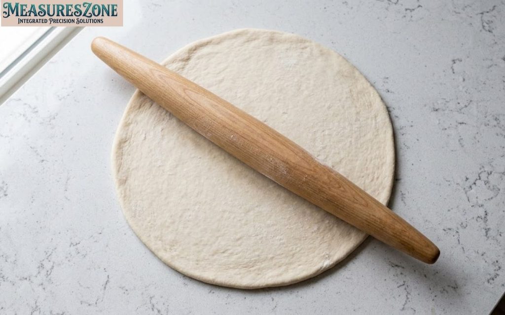 Wooden rolling pin on flattened dough.