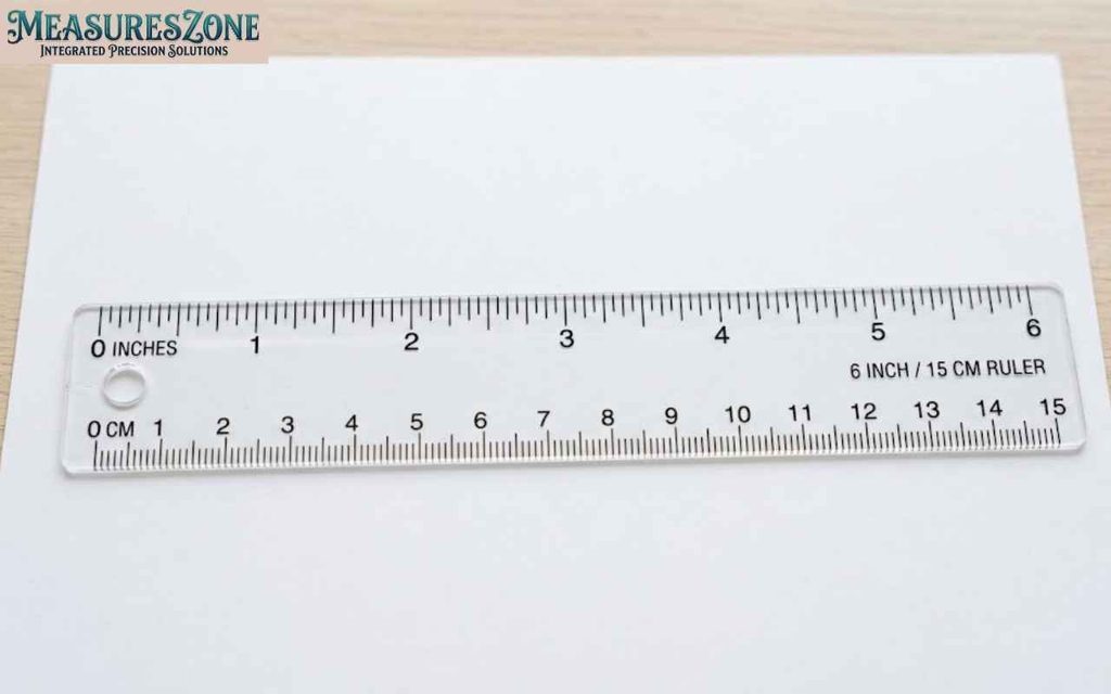 A clear plastic 6-inch and 15-centimeter ruler resting horizontally on a sheet of blank white paper.