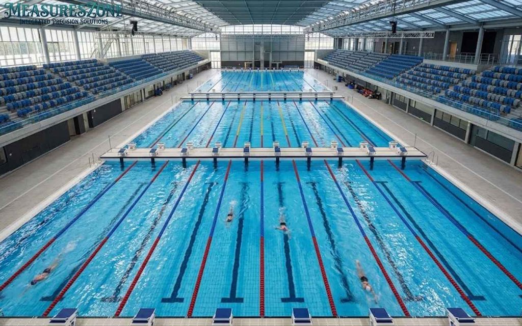 High-angle view of three Olympic pools in a modern indoor aquatic center.